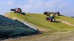 Anhäufung von Maissilage zur späteren Vergärung in einer Biogasanlage bei Lübeln (Wittingen). Verschiedene Traktortypen bei der Arbeit.  