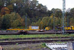 Ein Drehgestell-Flachwagen, Nummer unbekannt, der Gattung Res als Kran-Schutzwagen gegenlastseitig, u. a, beladen mit Werkstattcontainer, kleine Traversen, Anschlagmittel und sonstiges Zubehör/Equipment, sowie rechts der vierachsige Gegenlastwagen D-HGUI 99 80 9310 032-4 auf der einen Seite mit dem abgelegten Gegengewicht des 150 t Gleis- und Eisenbahndrehkran (EDK) KIROW Multi Tasker KRC 1200, D-HGUI 99 80 9419 041-5 „IDEFIX“ der HERING Bahnbau GmbH und auf der anderen Seite stützt, sich hier in der Transportstellung, das Gegengewicht-Teleskop hydraulisch auf dem Gegenlastwagen ab.

Abgestellt am 19 Oktober 2025 im Rbf Betzdorf/Sieg.