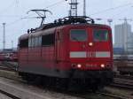 151 141-9 bei der Durchfahrt im Haltepunkt Rostock Toitenwinkel.Im Hintergrund stehen abgestellte Lok´s sowie eine ozeanblau-beige 140er und recht´s sind IC-Wagen zusehen.(22.04.06)