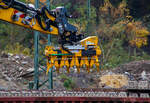 Schwellenverlegegerät Typ 159-5 (Hersteller Sonnenberg GmbH) am 08 November 2025 an einem LIEBHERR Zweiwegebagger A 922 Rail Litronic der SPITZKE SE (Großbeeren) im Rbf Betzdorf/Sieg. Hier werden zurzeit Gleise erneuert.

Der Schwellenleger ist eine innovative Neuentwicklung in Sachen Verlegetechnik. Durch das mittige Aufnehmen der Schwellen ist ein Anlegen an eine Lehrschiene möglich, wodurch kein Ausrichten der Schwellen mehr erforderlich ist.

•	Einfache Einstellung des Schwellen Typs und des Verlegeabstandes durch ein Bolzensystem.
•	Schwellentyp: Grobeinstellung der Schwellenbreite und Höhe in 10 mm Schritten. Feineinstellung der Schwellenbreite über ein Gewinde möglich.
•	Verlegeabstand: Grobeinstellung in 18 x 5 mm Schritten, Feineinstellung und größere Maß-Sprünge über ein Gewinde.
•	Die Greifer sind aus hochfestem und verschleißbeständigem Stahl (Hardox) gefertigt. Für einen besonders schonenden Umgang mit den Schwellen sind sie mit einem Hochleistungskunststoff ausgestattet.
•	Wartungsfreie und selbstschmierende Gleitkörper und Buchsen reduzieren den Wartungsaufwand auf ein Minimum.
•	Die Greiferzylinder sind mit Lasthalteventilen ausgerüstet um maximale Sicherheit zu gewährleisten.

TECHNISCHE DATEN:
Traglast: 3.300 kg
min. Schwellenbreite: 280 mm
max. Verlegeabstand: 750 mm
Gewicht Variante 159–5 für 5 Schwellen:  ca. 700 kg
Kleinste Transportabmessung (Variante 159–5): 1550 x 1000 mm
