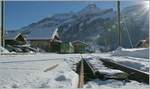 Vom Bahnübergang einen Gegenlichtblick auf den Bahnhof von Les Diablerets mit einem dort auf die Abfahrt nach Aigle wartenden ASD Regionalzug.