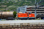 Aus dem Zug heraus, die Em 3/3 163  Rene  (98 85 5837 910-9 CH-LONZA) eine Henschel DHG 500 C der Lonza Group AG (Visp), am 26.05.2023 mit einem Kesselwagenzug im Bahnhof Visp.