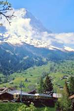 Ein Zug der Wengernalpbahn fährt im Mai 1981 von Grindelwald Grund hinauf nach Grindelwald, im Hintergrund der 3.970 m hohe Eiger