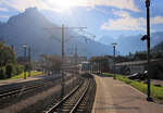 Zentralbahn, Strecke Luzern - Engelberg: Im grellen morgendlichen Gegenlicht am Fusse einer imposanten Berglandschaft steht ein Zug in Engelberg bereit für die Rückfahrt nach Luzern.