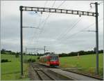 Der CJ GTW au der Fahrt nach Glovelier wird von einem Fahrleitungsmast der Station La Cibourg eingerahmt.