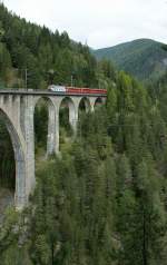 Ge 4/4 III hat mit ihrem Regionalzug nach Filisur die Station Wiesen verlasen und fhrt nun auf den eindrcklichen Viadukt von Wiesen.