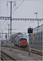 Die SBB Cargo Eem 923 028-5 steht mit einem gedeckten Güterwagen im Gleisvorfeld von Neuchâtel.